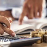 Man and woman hand consider on calculator expenses of family budget against home background. Lending purchase rental housing mortgage concept