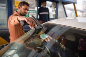 A toll employee scans a FASTag pass manually as the
